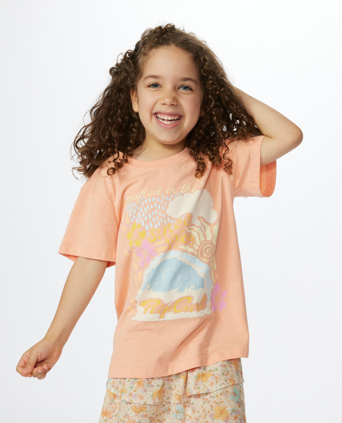 Maglietta Rip Curl Crystal Cover per bambina, color pesca, con stampa Rip Curl frontale.